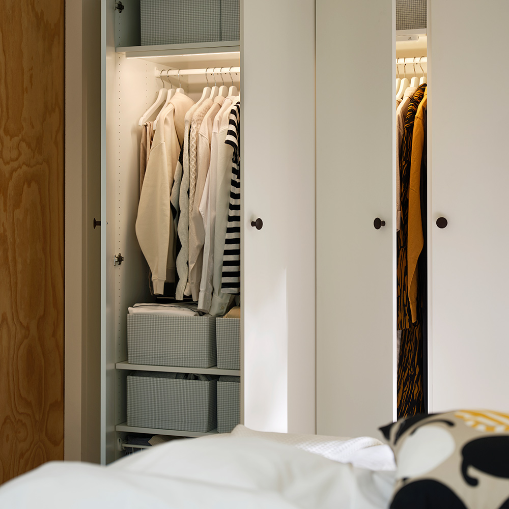 LASTARE wardrobe combination in white with open doors showing hanging clothes and storage boxes inside.