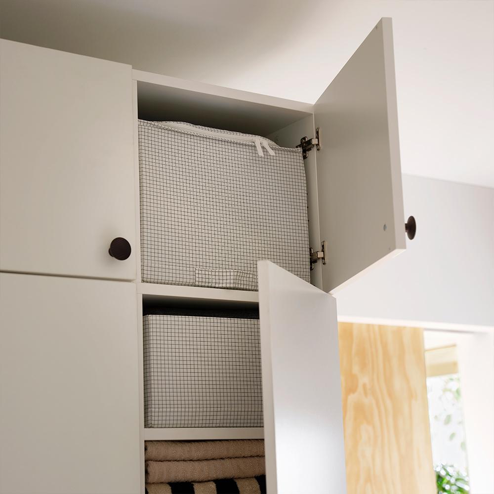 LASTARE wardrobe combination in white with open upper doors revealing STUK storage case and folded textiles.