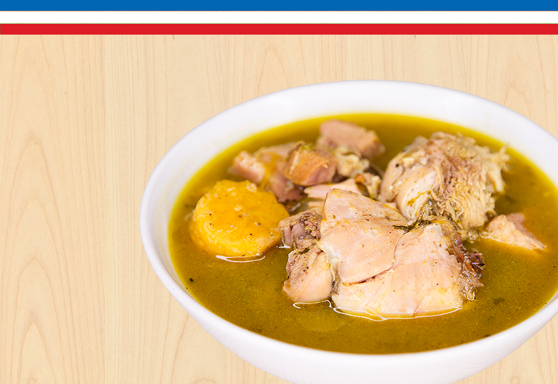 Plato de sopa de pollo caliente con verduras servido en un tazón blanco.
