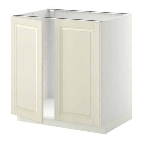 Un mueble de cocina METOD blanco con dos puertas biseladas en blanco roto. Tiene un marco robusto y bisagras a presión.