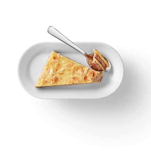 Una rebanada de bizcocho de almendras en un plato blanco, con una base crujiente de almendras y cobertura de nata.