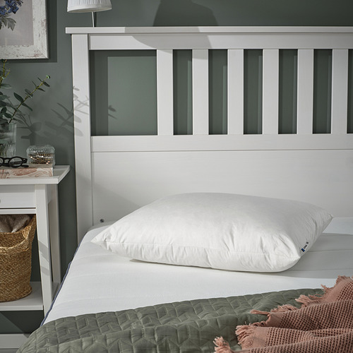 Acogedor dormitorio con almohada PILSPINNARE blanca, cesta de mimbre, edredón verde, cabecero blanco.