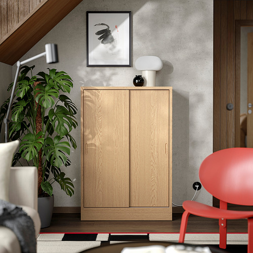 Mueble de roble TONSTAD con puertas correderas y estantes en habitación moderna.