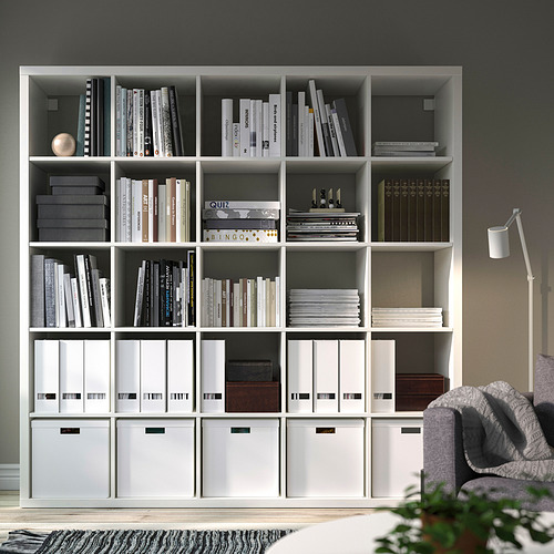 Estantería blanca KALLAX con libros y almacenamiento, sala divisoria y acogedor rincón de lectura.