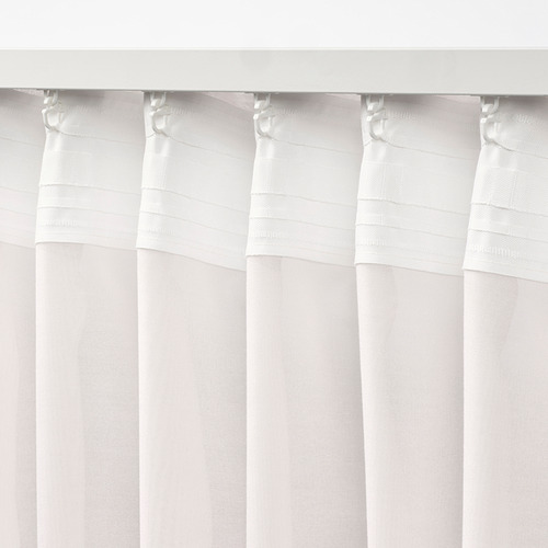 Cortinas STENFRÖ transparentes blancas con ganchos decorativos, creando pliegues suaves. Estas cortinas suavizan la luz del sol y brindan privacidad.