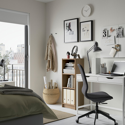 Una oficina en casa compacta con una estantería BILLY blanca, una silla de oficina gris y un escritorio con una computadora portátil y plantas.