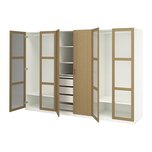 Un armario PAX de IKEA en blanco con detalles en roble. Abre y cierra secciones, estantes, cajones y una bandeja extraíble para accesorios.