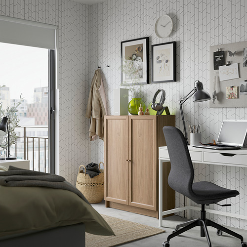 Dormitorio moderno con estantería Billy, escritorio y silla de oficina, cama con almohada verde.