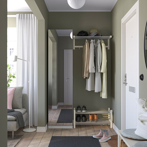 Entrada con pared verde, estante para chaquetas, estante para zapatos y zona de asientos gris.