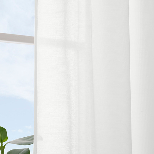 Cortinas blancas transparentes cuelgan de una ventana, difundiendo la luz del sol para mayor privacidad y suavizando el resplandor de las pantallas.