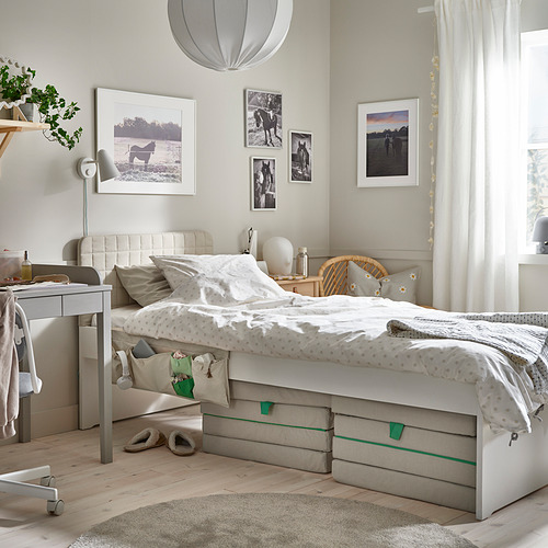 Dormitorio para niños con cama blanca, silla de mimbre y fotos.