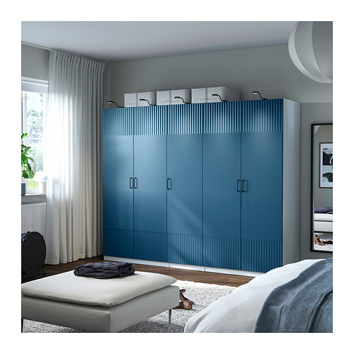 Dormitorio moderno con gran armario PAX azul, cama y cortinas blancas.