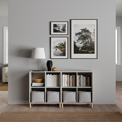 Salón minimalista con decoración gris, lámpara blanca, estantería, fotos y artículos de decoración.