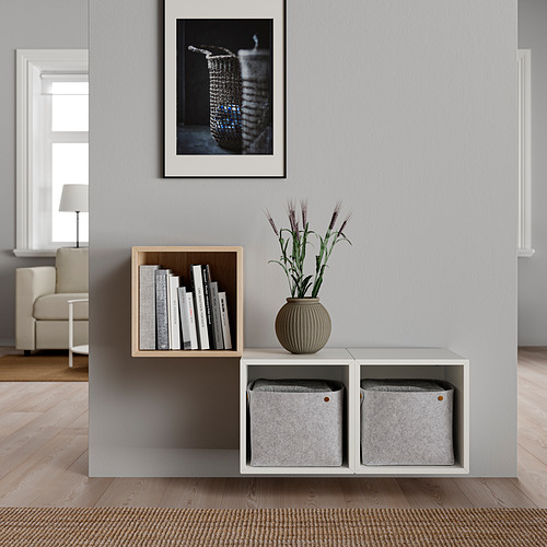 Estantería minimalista de pared con cajas grises, una estantería y un jarrón con flores, decoradas con un diseño neutro y moderno.