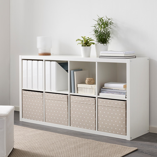 Estantería kallax blanca con cajas de almacenamiento enjoyadas, que contienen libros, plantas y decoración.