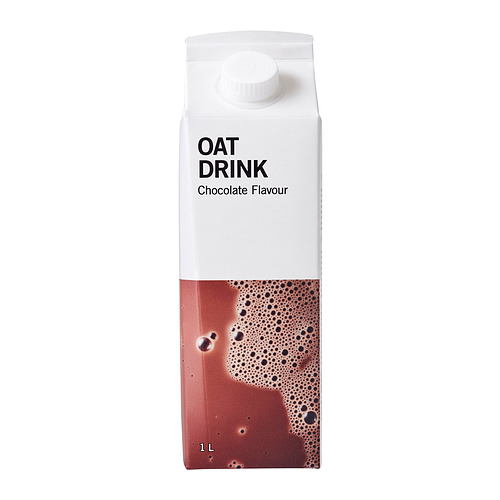 Cartón de bebida de avena con chocolate. Tapa blanca en la parte superior, líquido marrón visible a través de la sección transparente.