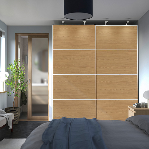 Dormitorio moderno con gran armario PAX de roble. Decoración neutra, cama azul, puerta de baño de cristal.