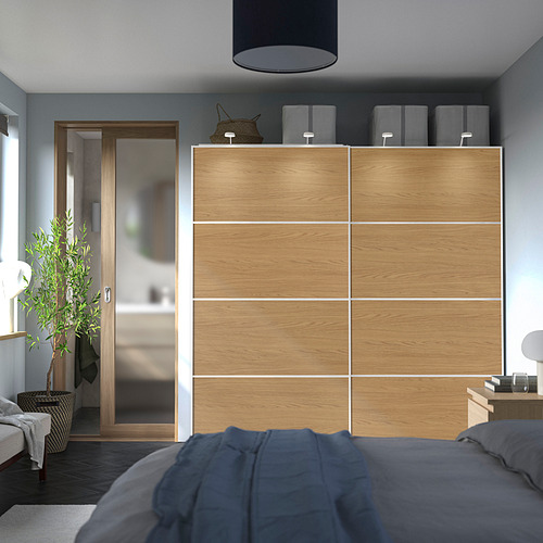 Dormitorio moderno con gran armario de madera para pax, cama azul oscuro y planta en maceta.