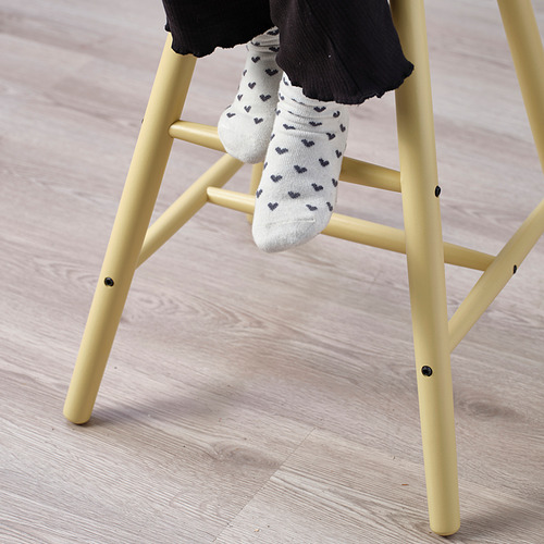 Silla para niños con calcetines blancos, se sienta sobre piso de madera.