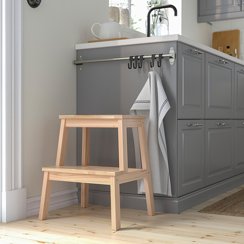 Taburete de madera BEKVÄM junto a armarios de cocina grises. Pequeño, de color claro, estable.