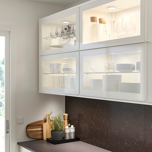 Cocina moderna con gabinetes de vidrio, mesada oscura, planta y accesorios.