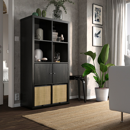 Estantería KALLAX negra con jarrones, plantas, junto a silla blanca.