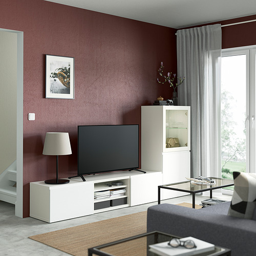 Sala de estar moderna con mueble de TV BESTÅ, lámpara, decoración, alfombra, mesa de centro, sofá, arte y cortinas.