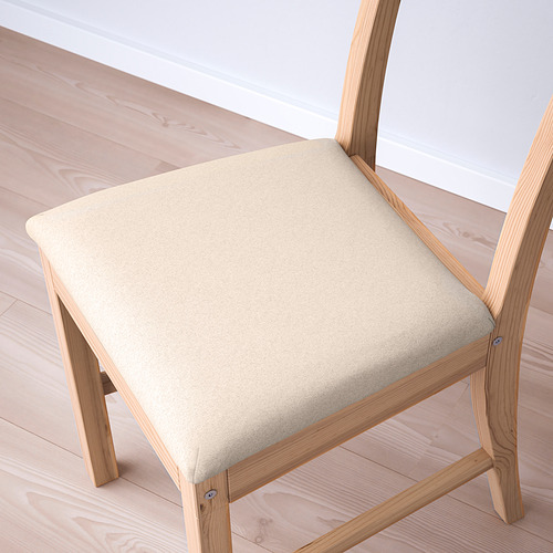 Silla moderna de madera en ángulo con asiento tapizado en color beige suave, sobre suelo de madera clara.