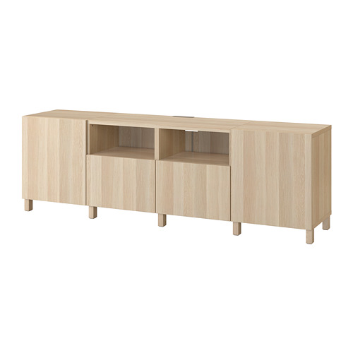 Un banco de televisión BESTÅ de color madera claro con estantes ajustables y gestión de cables, con un diseño elegante y almacenamiento funcional.