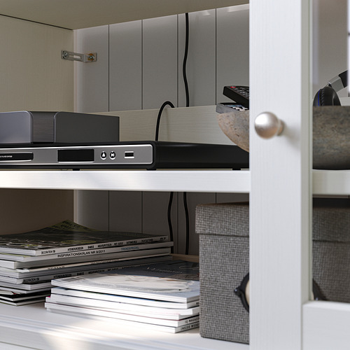 Estantería de madera blanca con aparatos electrónicos, libros y artículos decorativos cuidadosamente dispuestos.