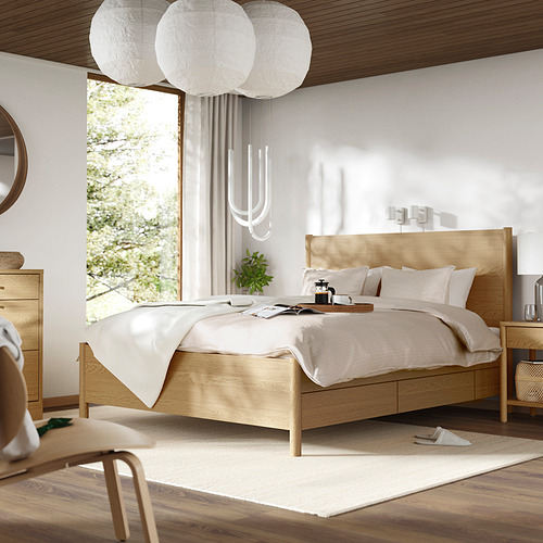 Cama TONSTAD de madera clara con cuatro cajones, elegante e imponente, que se funde con la decoración neutra y la luz natural.