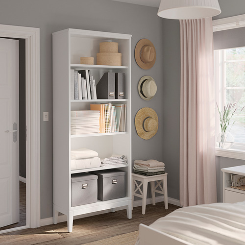 Dormitorio moderno con estantería blanca, sombreros y ropa doblada de IDANÄS.