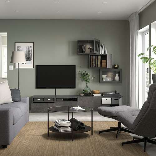 Sala de estar moderna con mueble de TV SINDVIK gris, sofá gris, mesa de centro de cristal y sillón gris. Pared de acento verde con estantes.