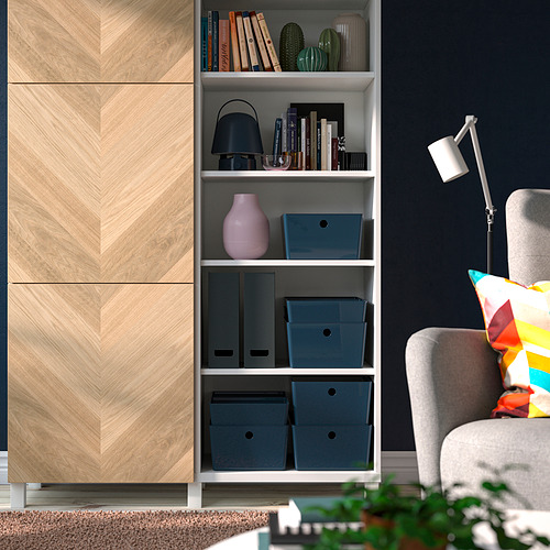 Cajas de almacenamiento azules de KUGGIS en estanterías blancas con archivos y decoración, sofá gris, lámpara negra, armario de madera.