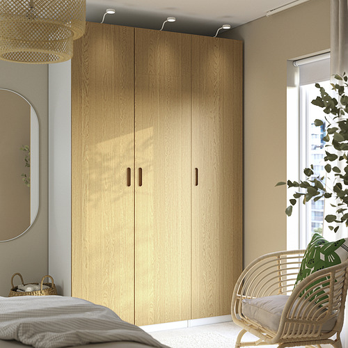 Dormitorio moderno con gran armario de chapa de roble TONSTAD, silla de mimbre y planta.