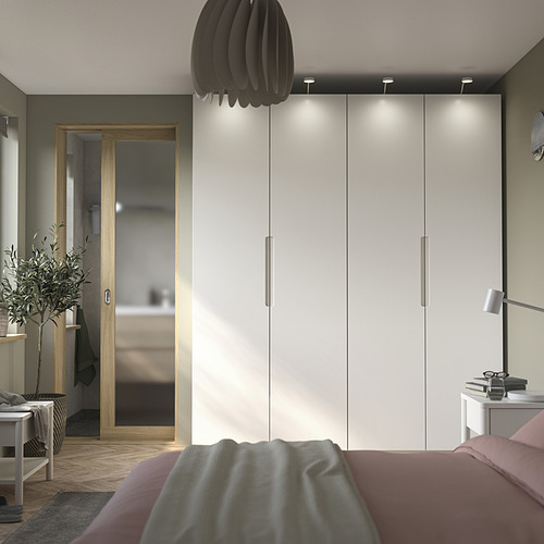 Dormitorio moderno con armario PAX, iluminación integrada y una planta en maceta.
