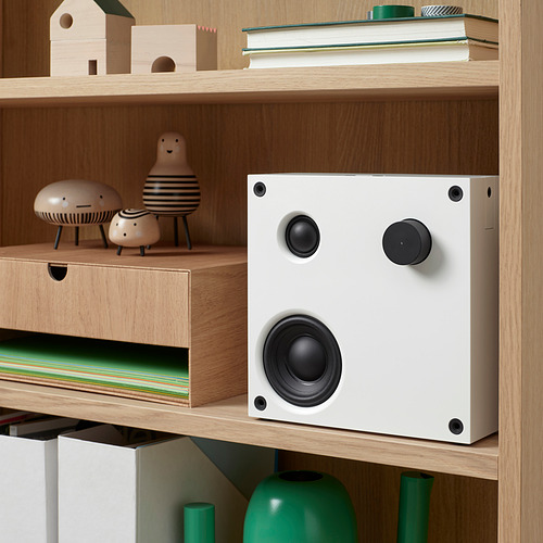 Una estantería moderna con un altavoz bluetooth VAPPEBY blanco, perillas y elementos decorativos.