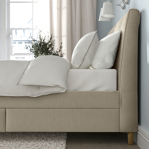 Cama tapizada con cabecero inclinado, cajones y almohadas.
