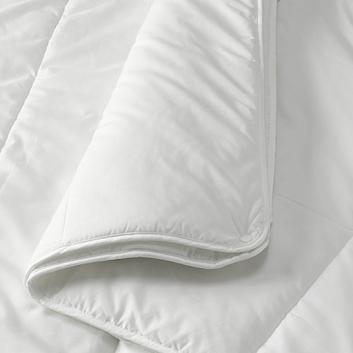 Primer plano de un edredón blanco en la cama, que muestra el borde con costuras, tela lisa y relleno regordete, uniforme.