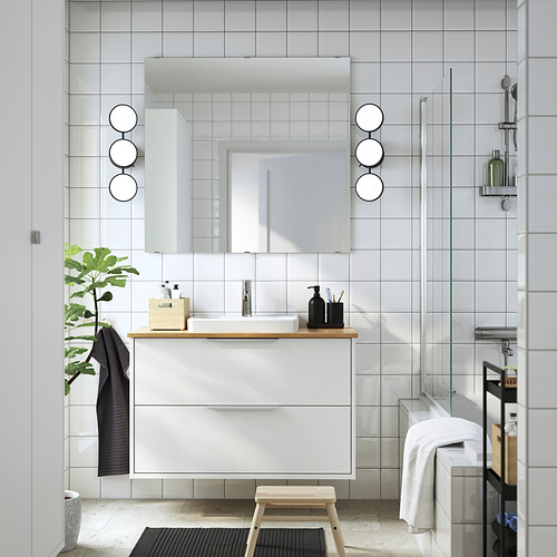 Baño moderno con mueble blanco ÅLSKEN, encimera de bambú, espejo rectangular, lavabo, planta y toallas. El tamaño del tocador encaja perfectamente debajo del espejo.