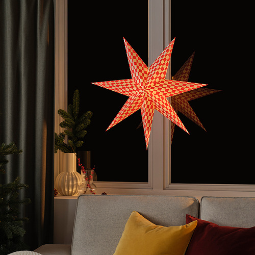 Decoración de estrella a cuadros rojos en ventana con cojines y planta.