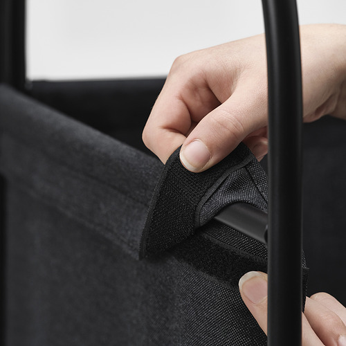 La imagen muestra una mano ajustando un cierre de velcro en la cubierta extraíble de un separador de ambientes de metal.