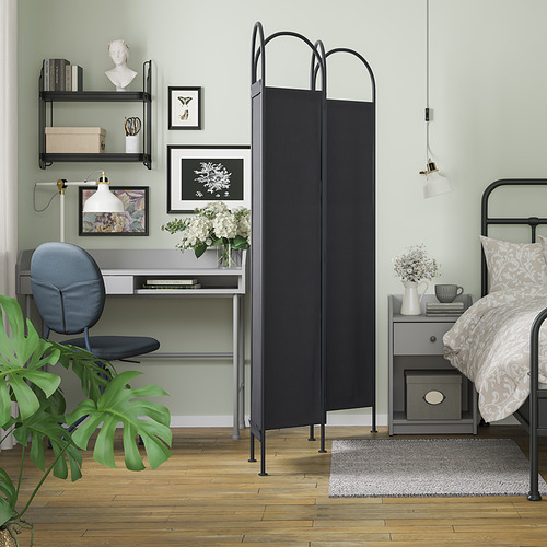 Dormitorio moderno con separador GRÅFJÄLLET negro, escritorio, cama, estanterías, planta, mesita de noche.
