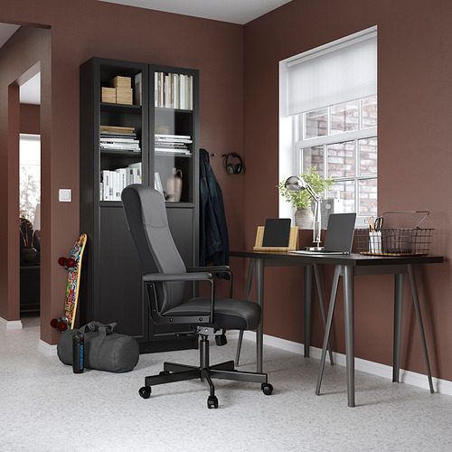 Configuración de oficina en casa con silla, escritorio y estantería negros contra paredes marrones, alfombra gris.