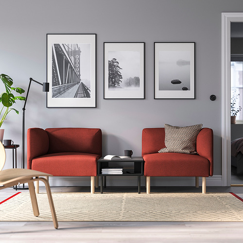 Sala de estar moderna con sofá seccional naranja, arte de pared gris, mesa de café, lámpara, planta y alfombra.