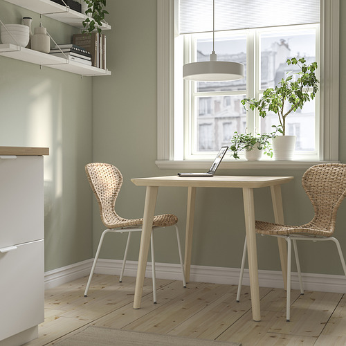 Mesa de comedor LISABO y sillas de mimbre junto a la ventana, ambiente acogedor.