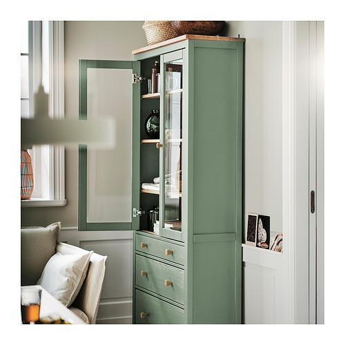 Mueble verde con puerta de cristal HEMNES con amortiguadores, estantes ajustables y decoración.
