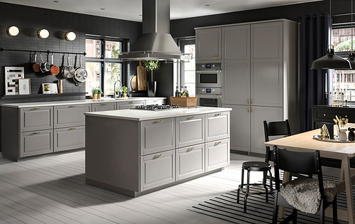 Cocina moderna con gabinetes BODBYN grises, isla de encimera blanca, electrodomésticos de acero inoxidable y luces colgantes.