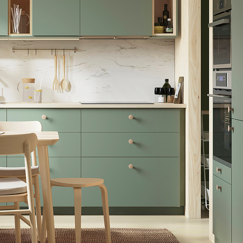 Cocina moderna con armarios de color verde claro y taburetes de madera. Los pomos son pequeños, redondos y están hechos de madera clara.