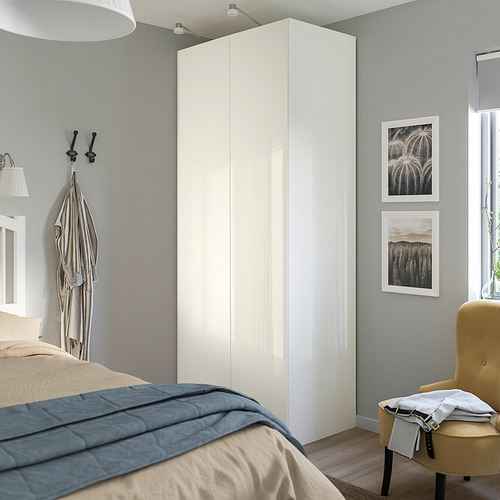 Dormitorio con armario FARDAL blanco brillante, alto y delgado junto a la cama.